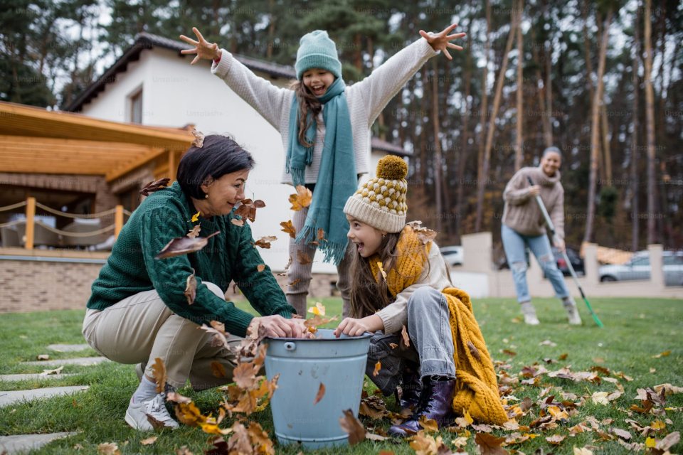 a family cleaning up leaves and wearing fall sweaters
