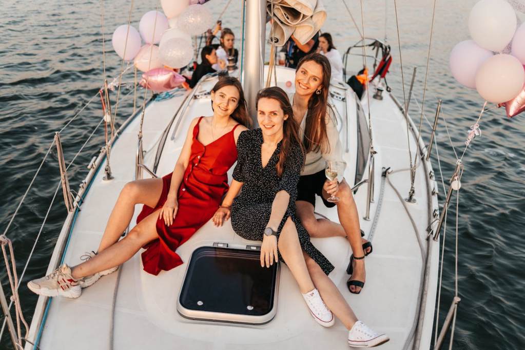 Women wearing summer wedding outfits on a boat