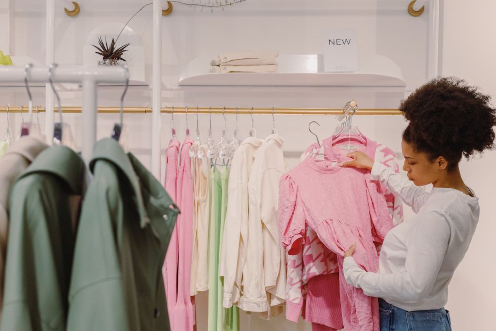 Woman holding a pink dress in a clothing showroom