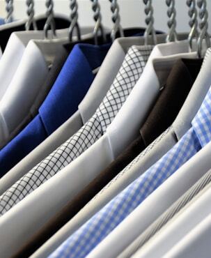 a row of men’s designer button down shirts on hangers